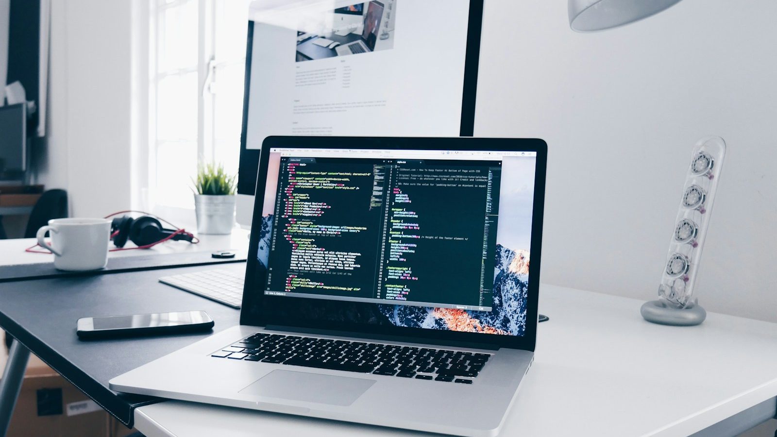 Laptop displaying web development code in a modern workspace